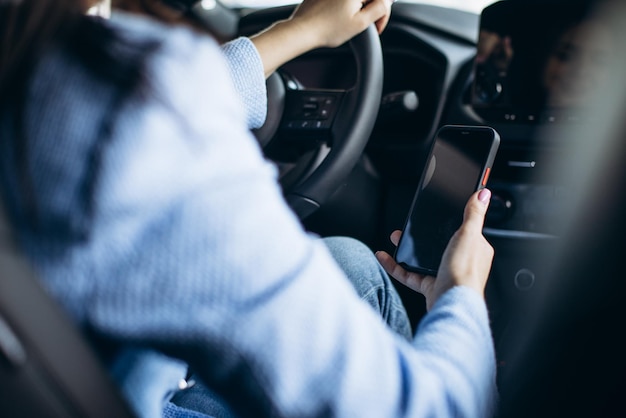 Foto gratuita donna che utilizza il telefono durante la guida in auto