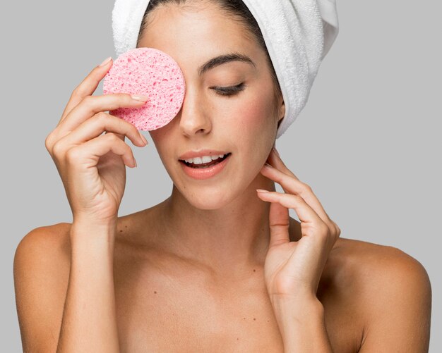 Woman using a pink sponge and looking down