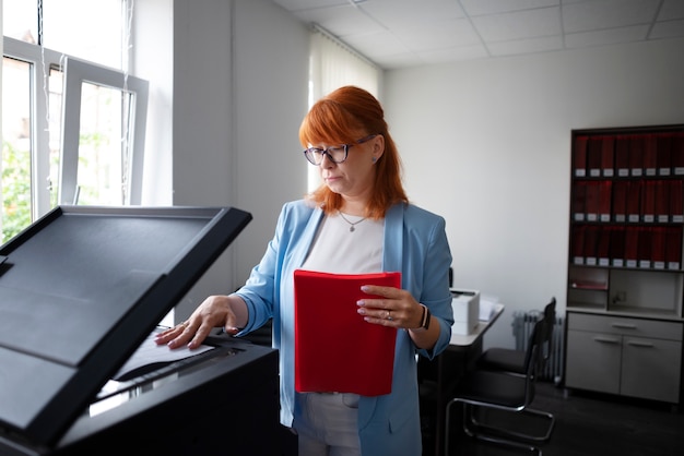 Foto gratuita donna che utilizza la stampante in ufficio