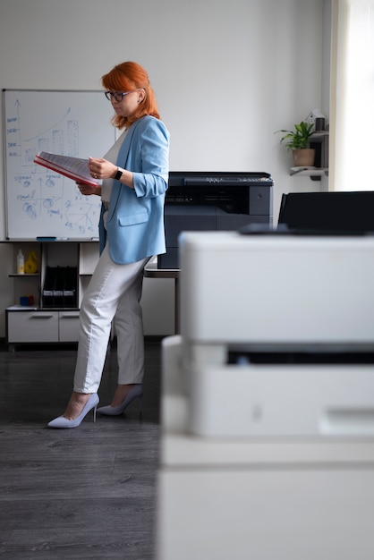 Foto gratuita donna che utilizza la stampante in ufficio