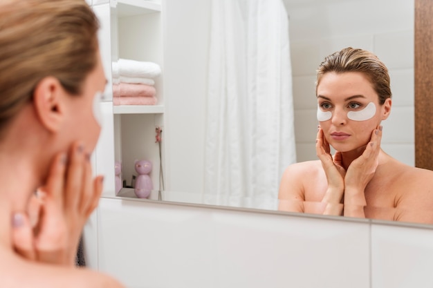 Woman using reducing dark circles patches in the mirror