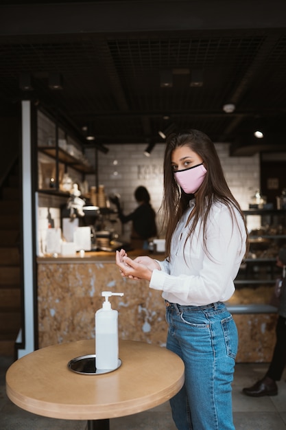 Woman using sanitizer gel cleans hands of coronavirus virus at cafe.