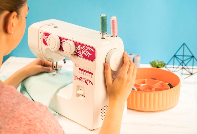 Женщина с помощью швейной машины на зеленой ткани