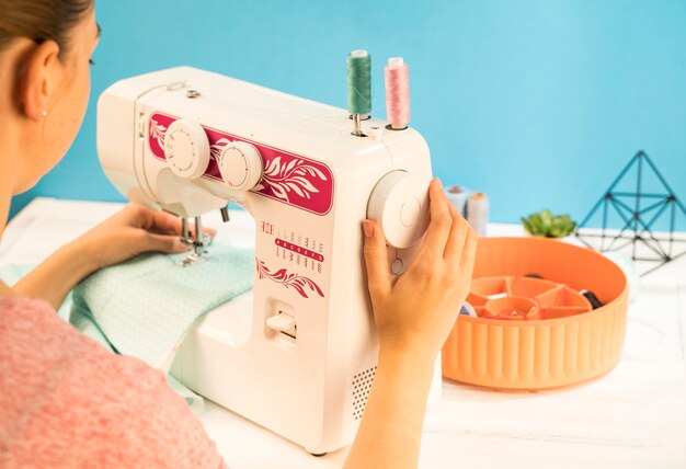 Woman using sewing machine on green fabric