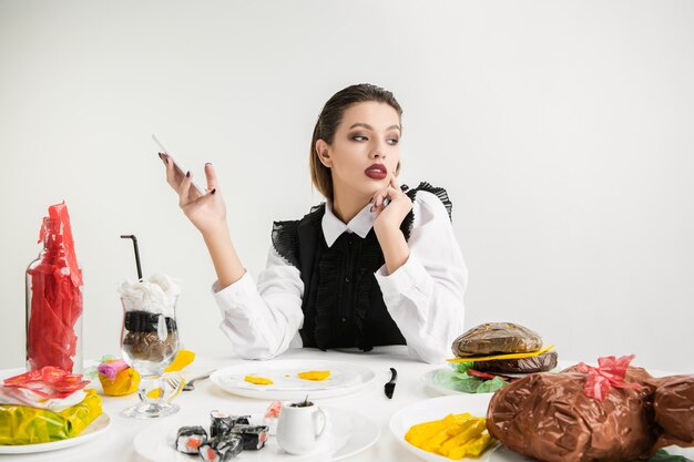 Woman using smartphone against dishes made of plastic, eco concept.