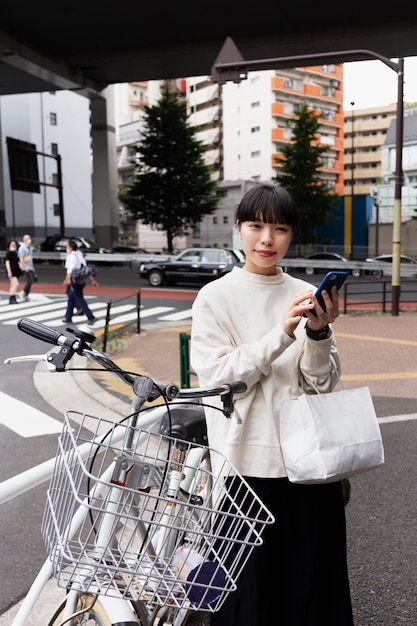 無料写真 市内でスマートフォンと電動自転車を使用している女性