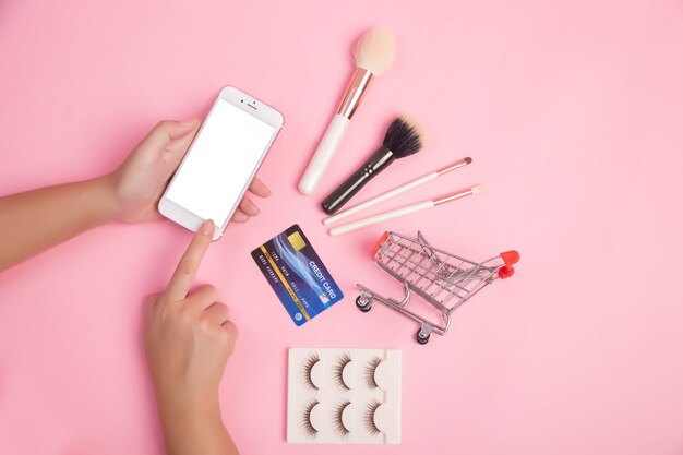 女性がスマートフォンやクレジットカードを使って美容アイテムをショッピング