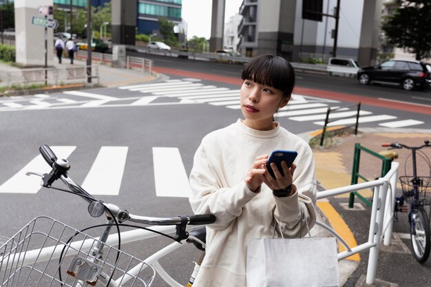 市内でスマートフォンと電動自転車を使用している女性