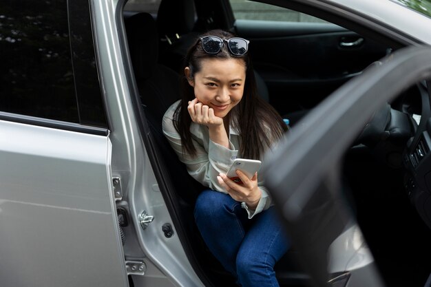 電気自動車でスマートフォンを使用している女性