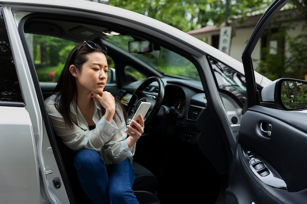 Woman using smartphone in electric car