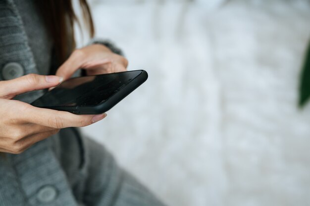 Woman using smartphone on her bed in cold day
