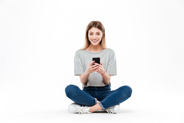 Woman using smartphone and sitting on floor