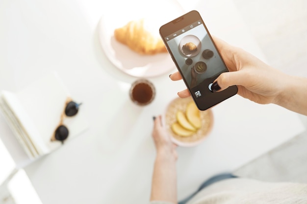 Женщина использует смартфон для фотографирования своей еды
