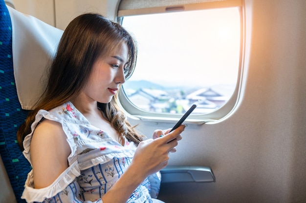 電車の中でスマートフォンを使用している女性。