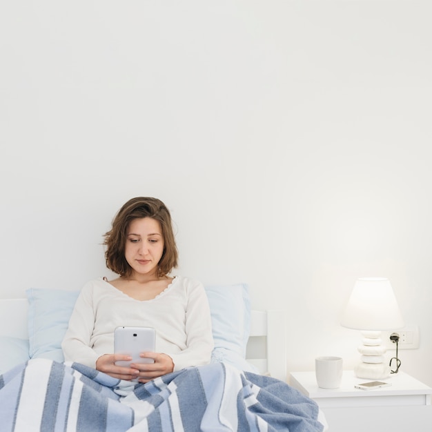 Free photo woman using smartphone while in bed