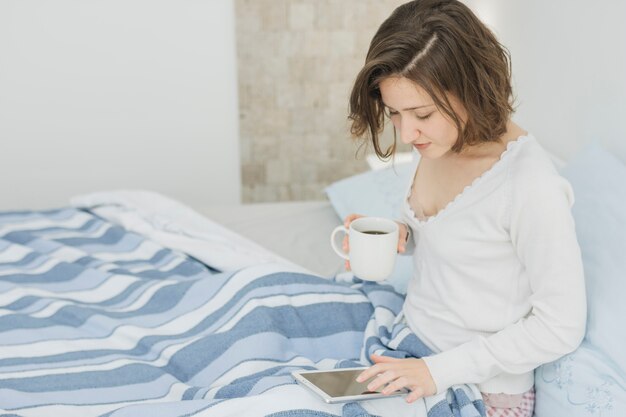 Женщина с помощью смартфона в постели