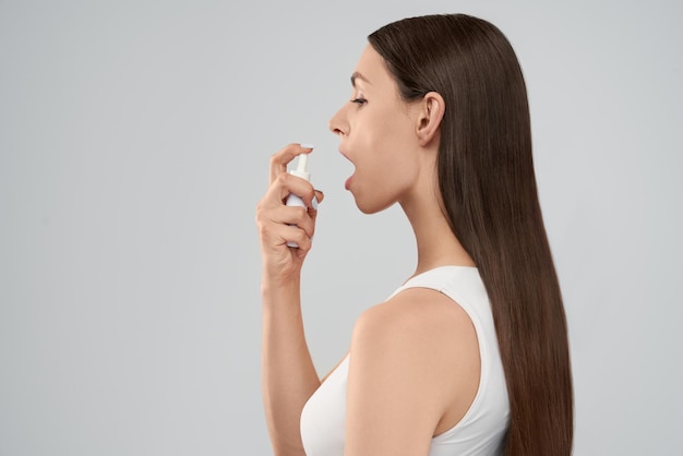 Woman using spray for throat