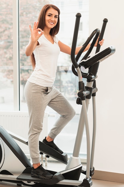 Foto gratuita donna che per mezzo di stepper e mostrando segno giusto