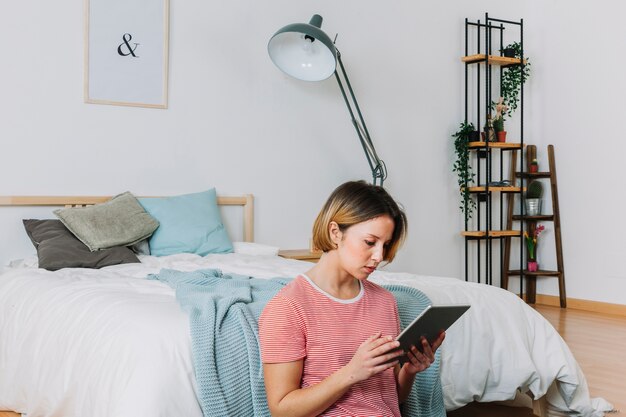 Woman using tablet on bedroom floor