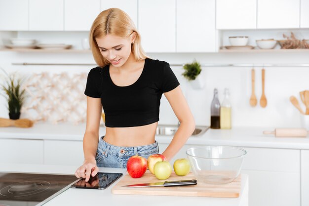Женщина с помощью планшетного компьютера на кухне