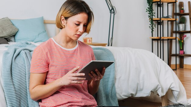 ベッドの近くでタブレットを使用している女性