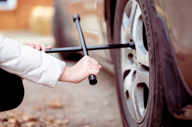 車のホイールにツールを使用している女性