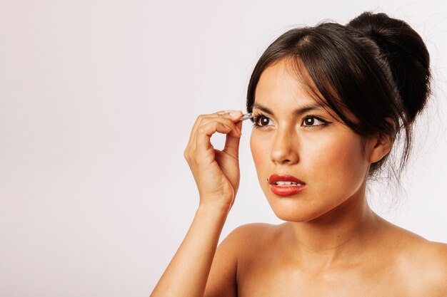 Woman using tweezers on her eyebrows