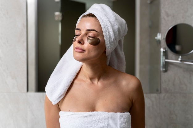 Бесплатное фото Женщина, использующая маски под глазами в ванной комнате