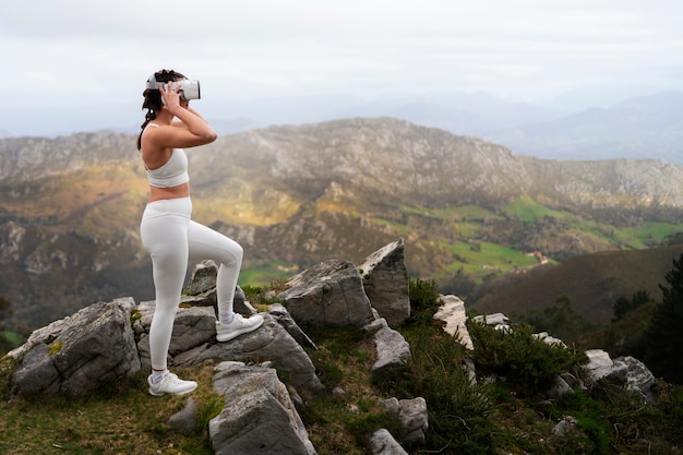 Foto gratuita donna che utilizza occhiali vr per esercitare all'aperto nella natura