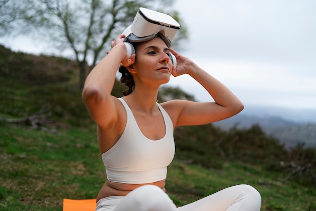 Free photo woman using vr glasses to exercise outdoors in nature