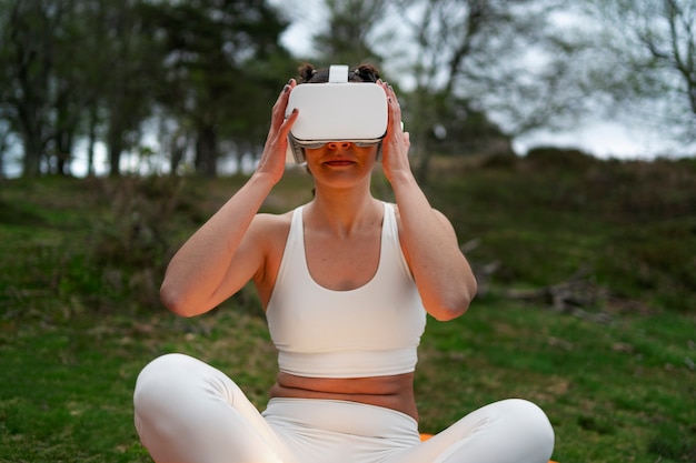 Foto gratuita donna che utilizza occhiali vr per esercitare all'aperto nella natura