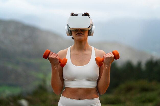 Woman using vr glasses to exercise outdoors with weights