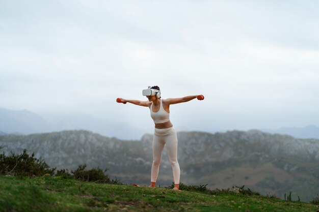 Woman using vr glasses to exercise outdoors with weights