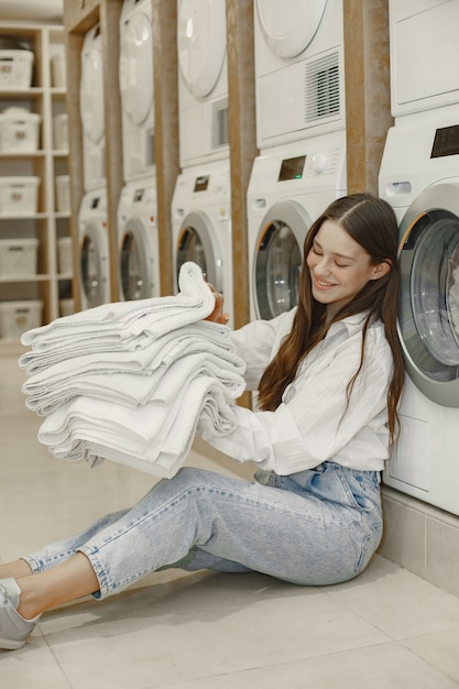 洗濯機を使って洗濯をしている女性。服を洗う準備ができている若い女性。インテリア、洗浄プロセスのコンセプト