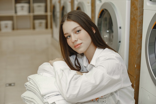 Free photo woman using washing machine doing the laundry. young woman ready to wash clothes. interior, washing process concept