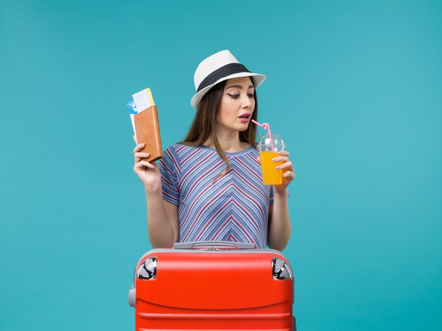 woman in vacation drinking fresh juice and tickets on blue