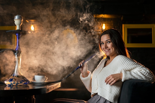 Free photo woman vaping from a hookah in a bar