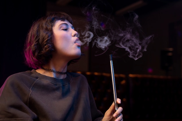 Woman vaping from a hookah indoors