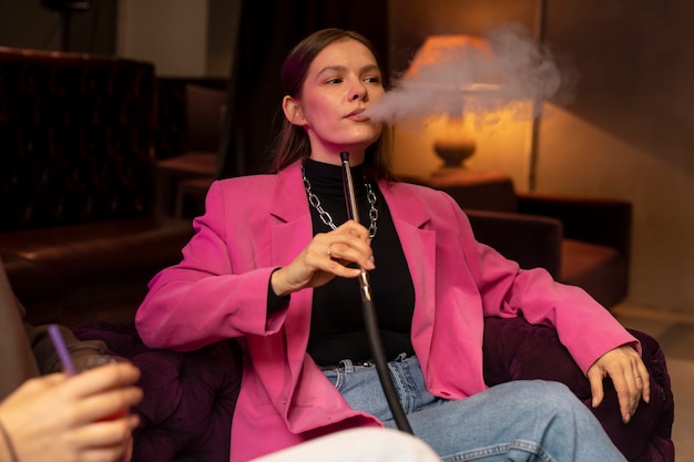 屋内で水ギセルからvapingする女性