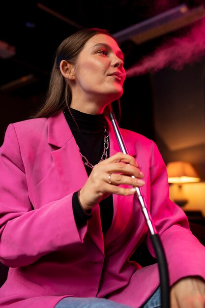 Woman vaping from a hookah indoors