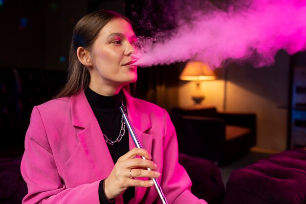 Woman vaping from a hookah indoors