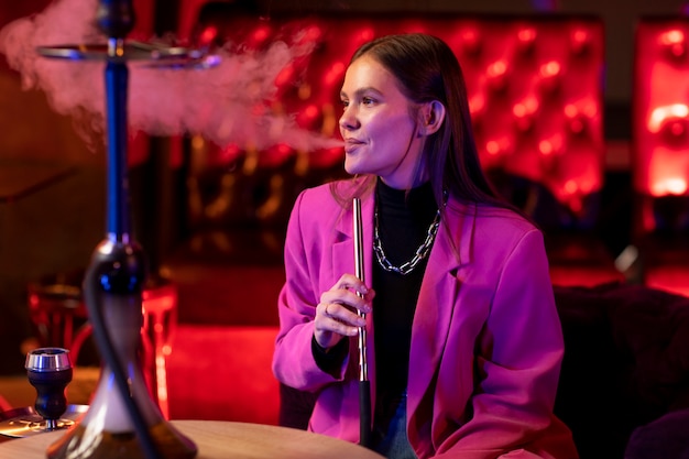Woman vaping from a hookah indoors