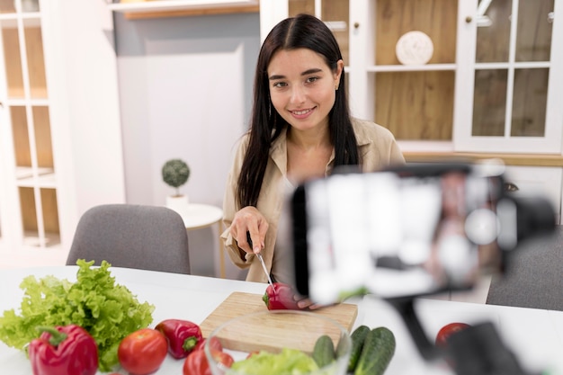 Foto gratuita donna vlogging a casa con verdure