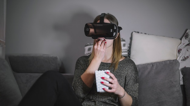 Woman in VR glasses eating popcorn