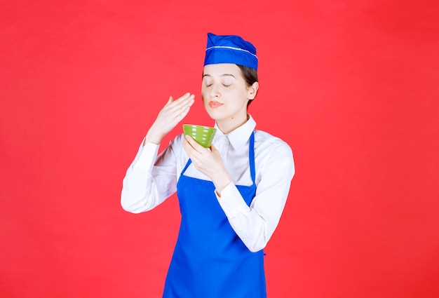 制服を着た女性ウェイトレスが立って、緑のボウルを保持しています。