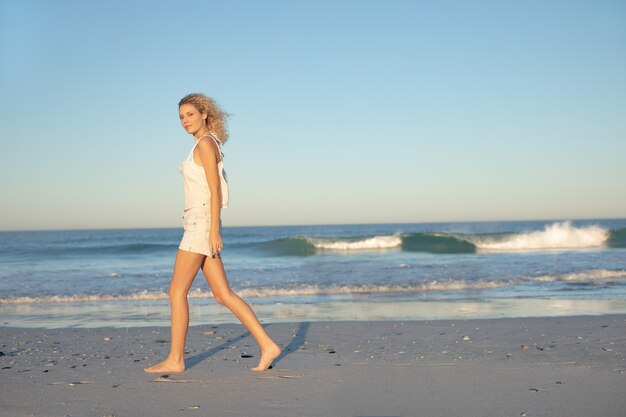 해변에서 맨발로 걷는 여자
