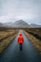 Free photo woman walking on a road in glen etive, scotland