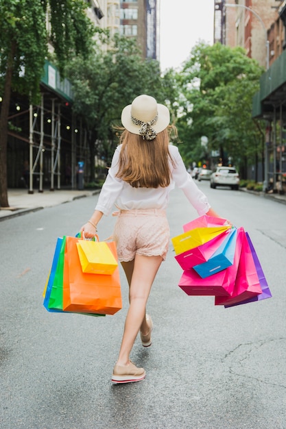Donna che cammina sulla strada con borse della spesa colorate
