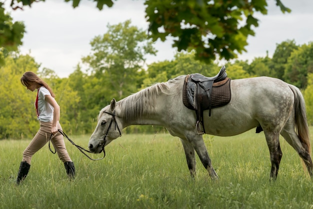 Donna che cammina con un cavallo sulla spiaggia