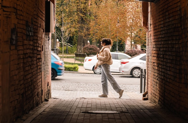 Free photo a woman walks along a city street a view from the alley a casual passerby